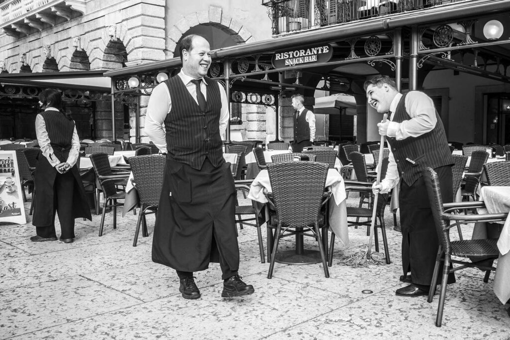 Camerieri che lavorano in allegria. Street Photography, Black and White.