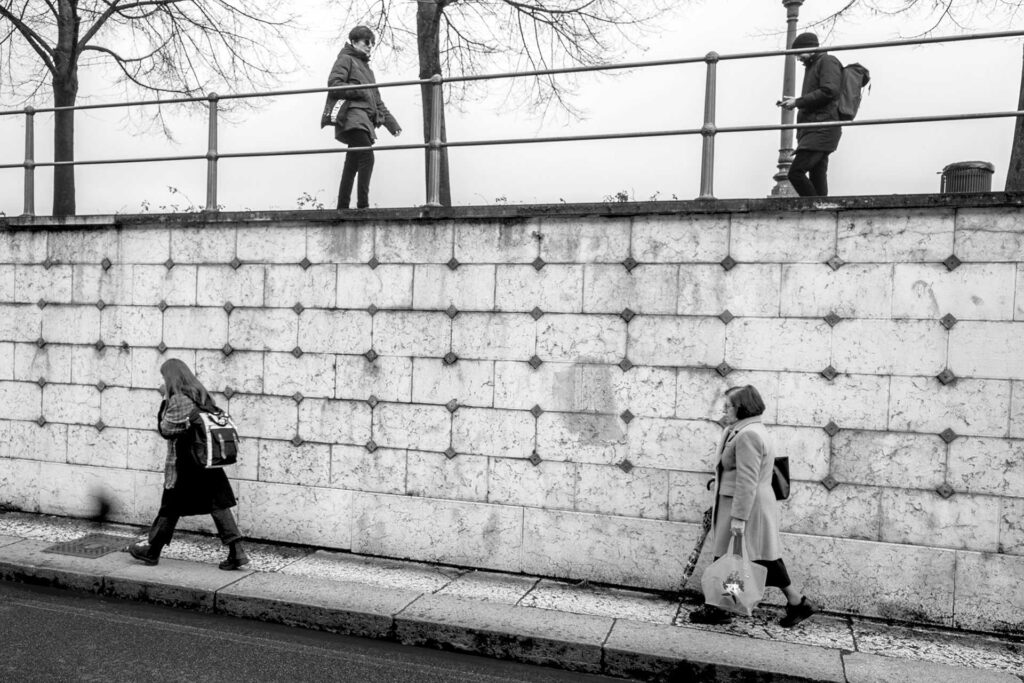 Quattro donne e un muro in equilibrio come quattro note su un tetragramma. Street Photography, Black and White.