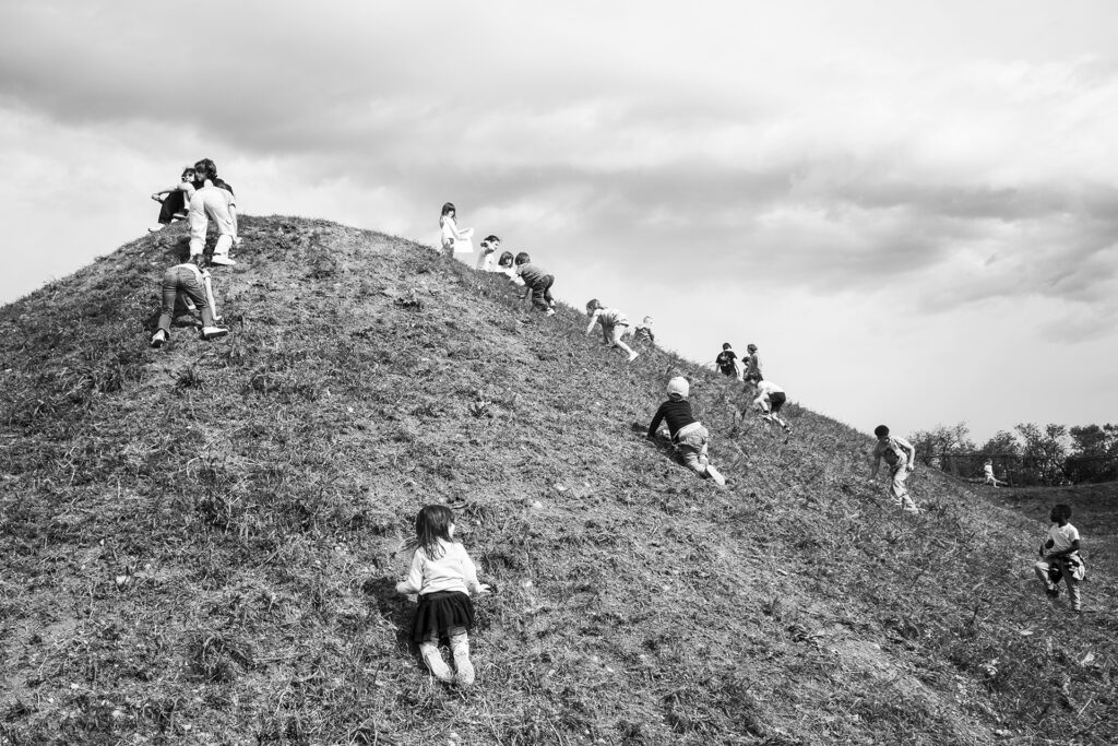 Bambini scalano una collina: la vita è una salita. Street Photography, Black and White.