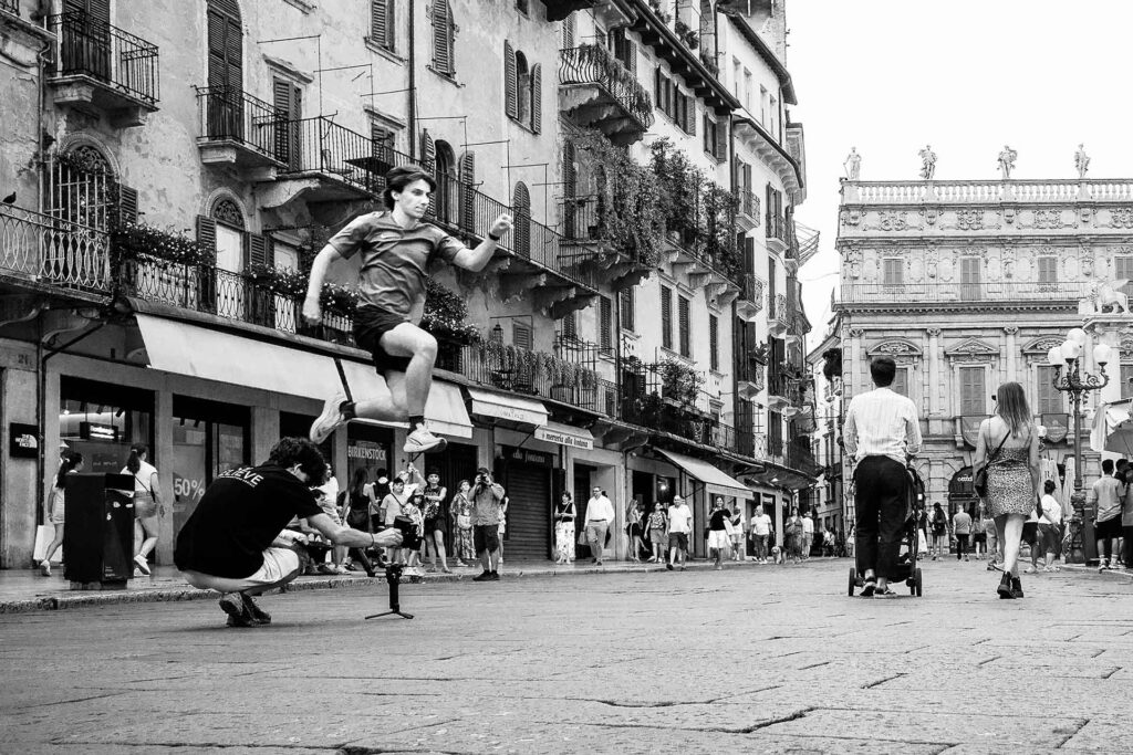 Un ragazzo fa un salto in piazza ripreso dalla telecamera. Street Photography, Black and White.