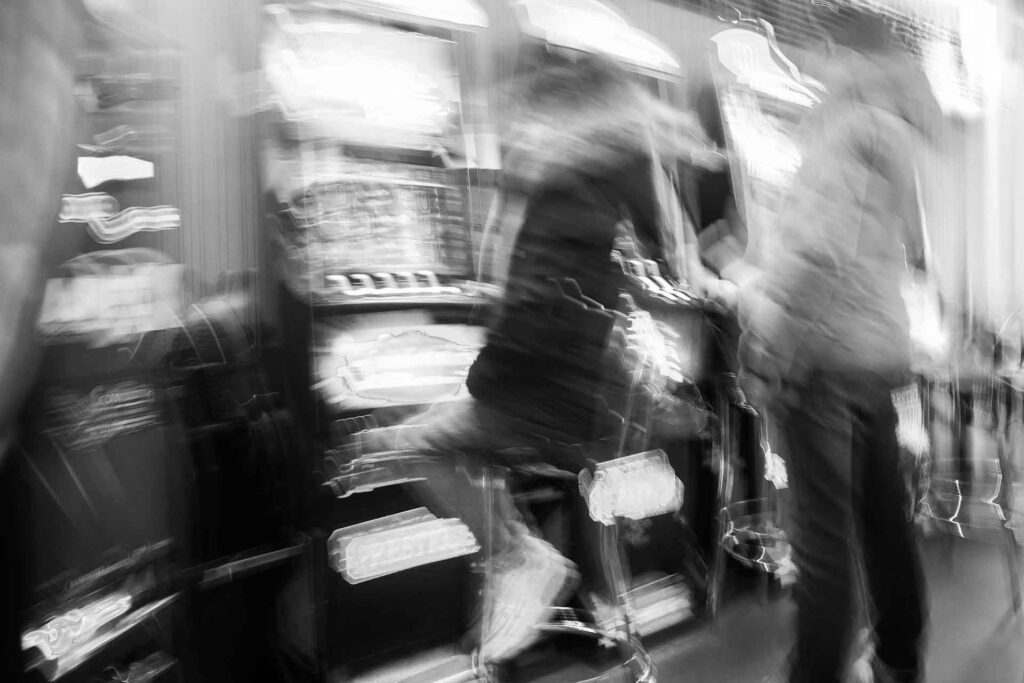 Foto sfocata di persone che giocano alle slot machine in un bar. Street Photography, Black and White.