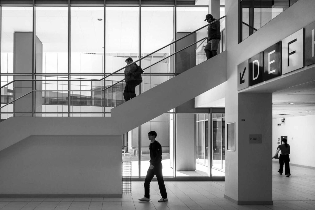 Siluette di persone con direzioni di movimento diverse all'interno di una struttura sanitaria. Street Photography, Black and White.